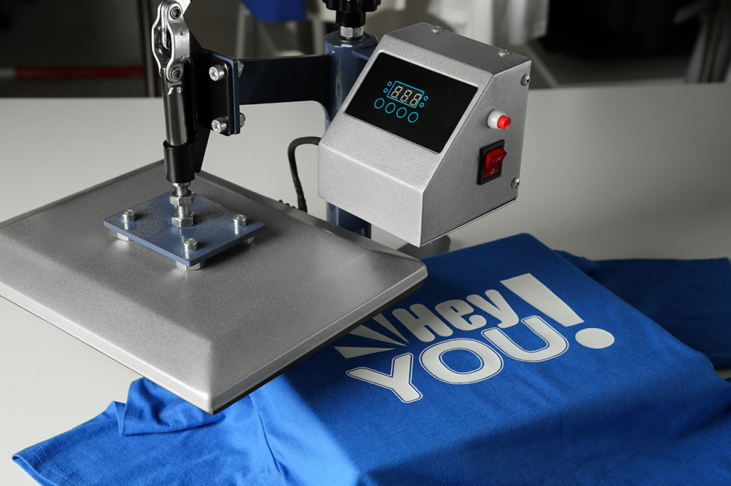 Printing logo. heat press with blue t shirt on white table, clos